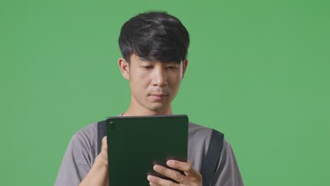 녹색 스크린 배경 스튜디오에서 는 동안 태블릿을 사용하는 아시아 남성 노동자의 근접