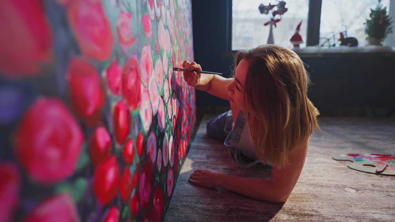 Ung kvinde maler levende blomsterkunstværk på stort lærred