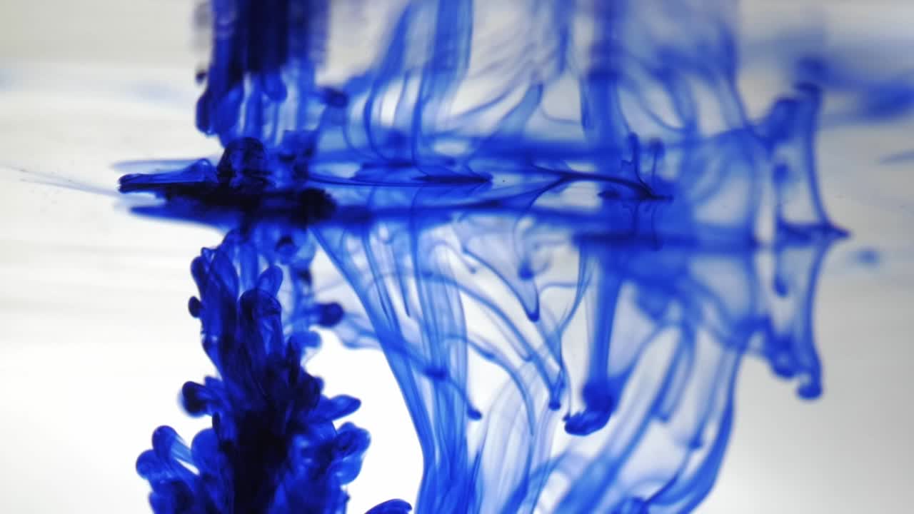 Reflection in an aquarium of blue smoke on a white background, spills of colored paint on a transparent liquid, drop of blue ink falling in water, drops of watercolor paint