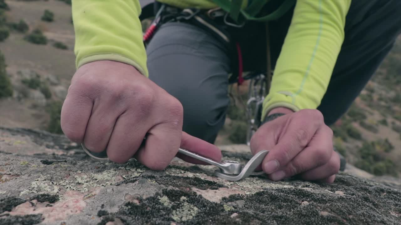 escalador atornillando un tornillo a una roca antes de escalar