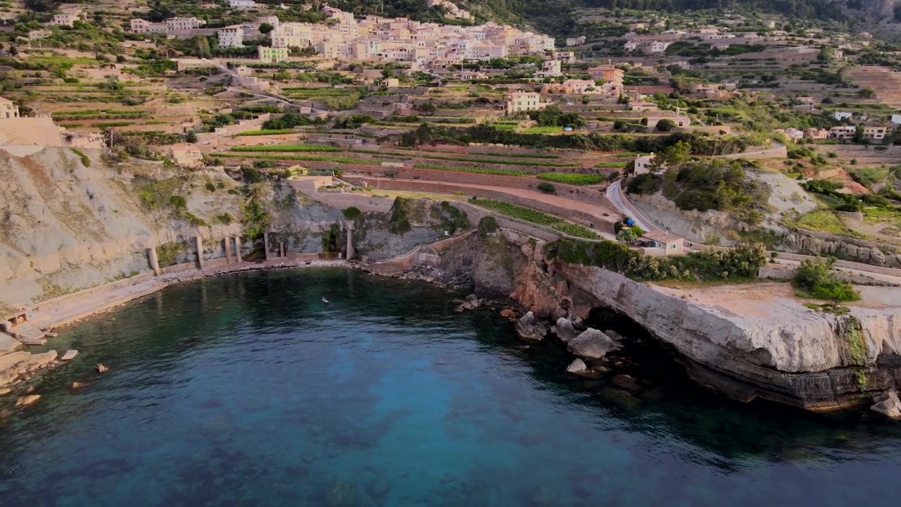 Explorez le magnifique paysage côtier de Banyalbufar à Majorque. Les eaux sereines reflètent la beauté des falaises environnantes et de la verdure luxuriante, créant une atmosphère pittoresque au coucher du soleil.