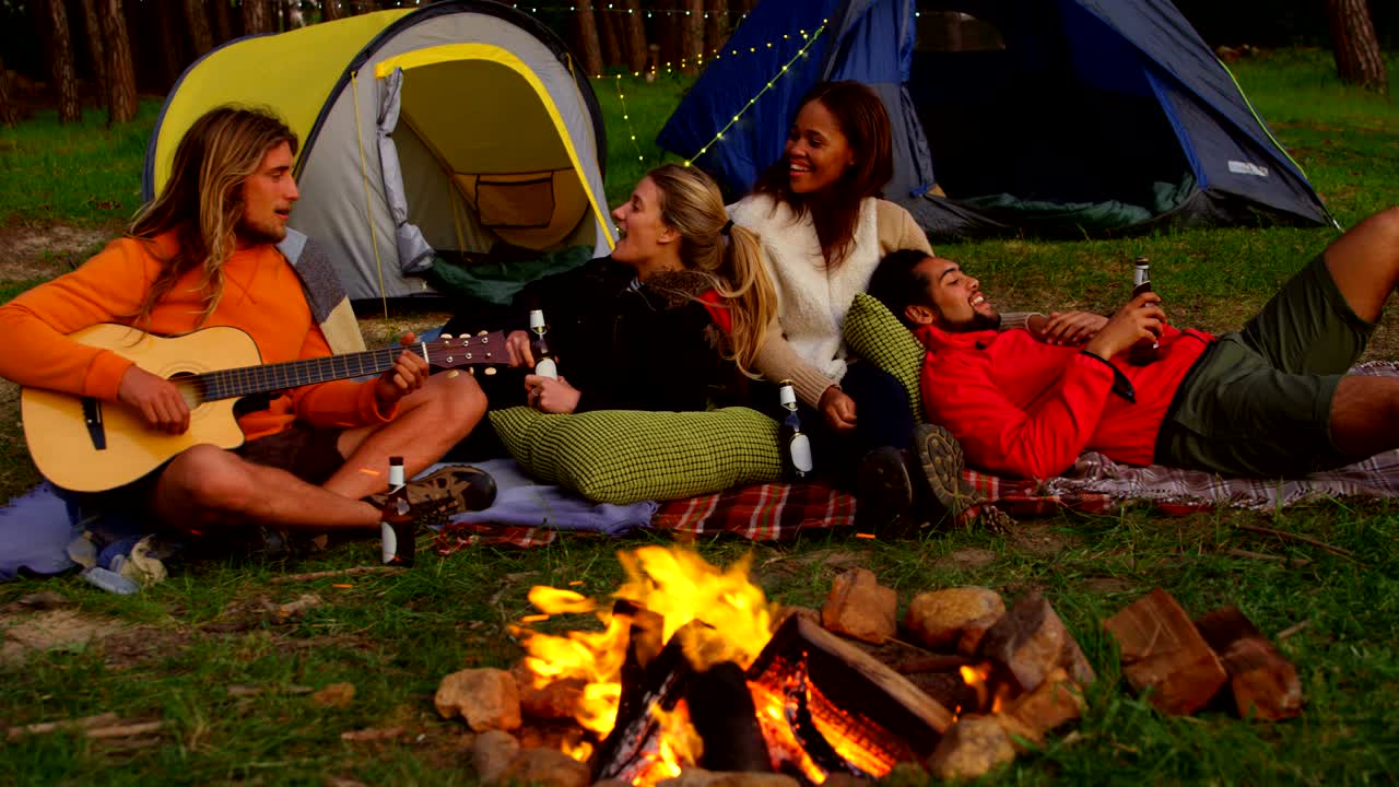 친구 들 이 숲 에 있는 캠프 불 근처 에서 즐기고 있다 4k