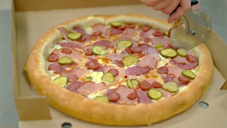 el cocinero corta la pizza cocida con tocino y salchicha ahumada con un cuchillo redondo especial