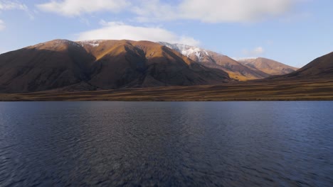 dolly aéreo volando rápido sobre el lago hacia montañas imponentes