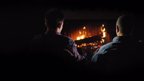 two handsome men rest by the fireplace slowly drinking brandy