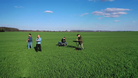 boys' band plays music in the green field. drone footage of the musicians first approaching them then distancing and flying aside. aerial view.