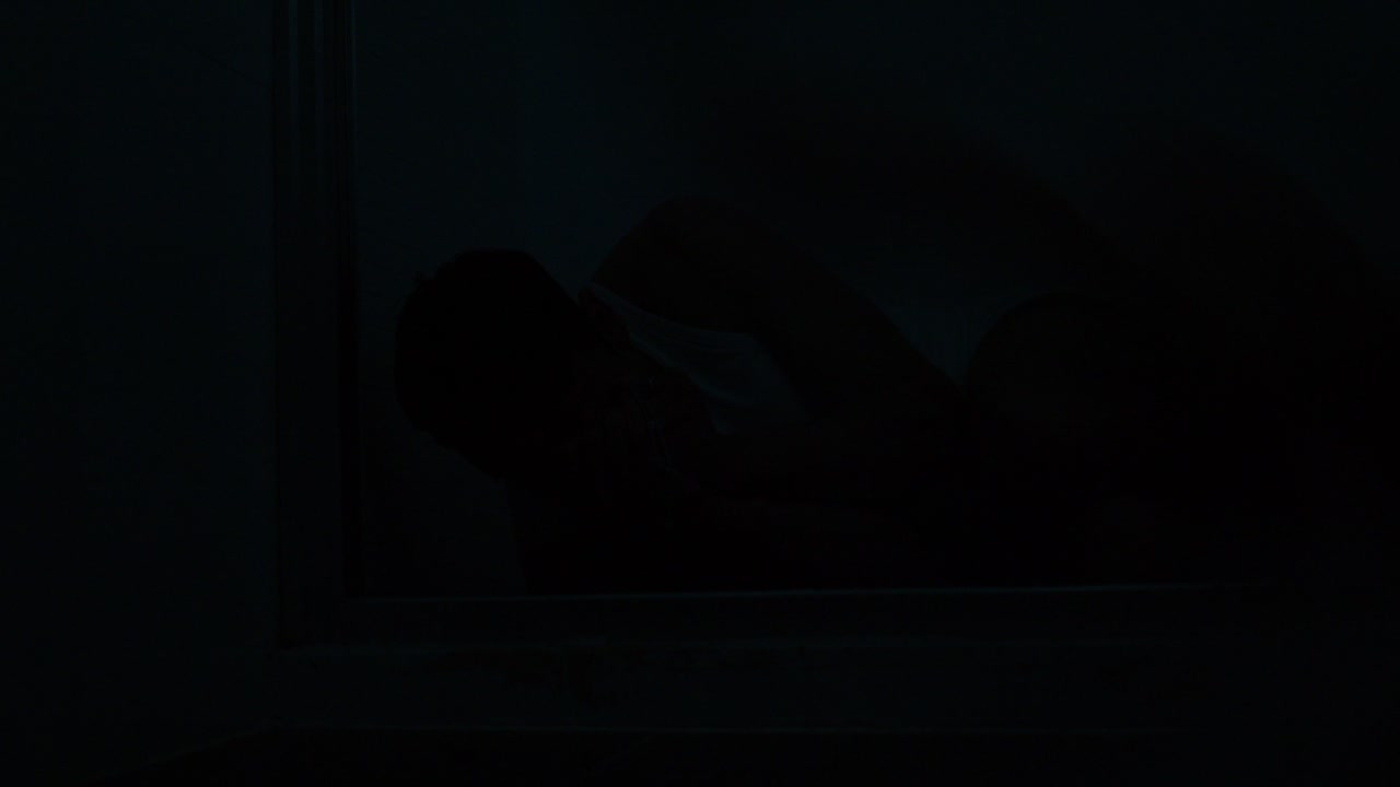 A distressed man is hiding in a dark corner