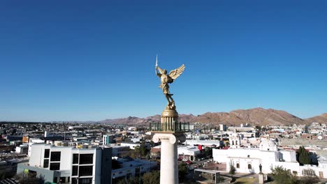 orbital drone shot of peace monument in chihuahua city downtown during sunrise