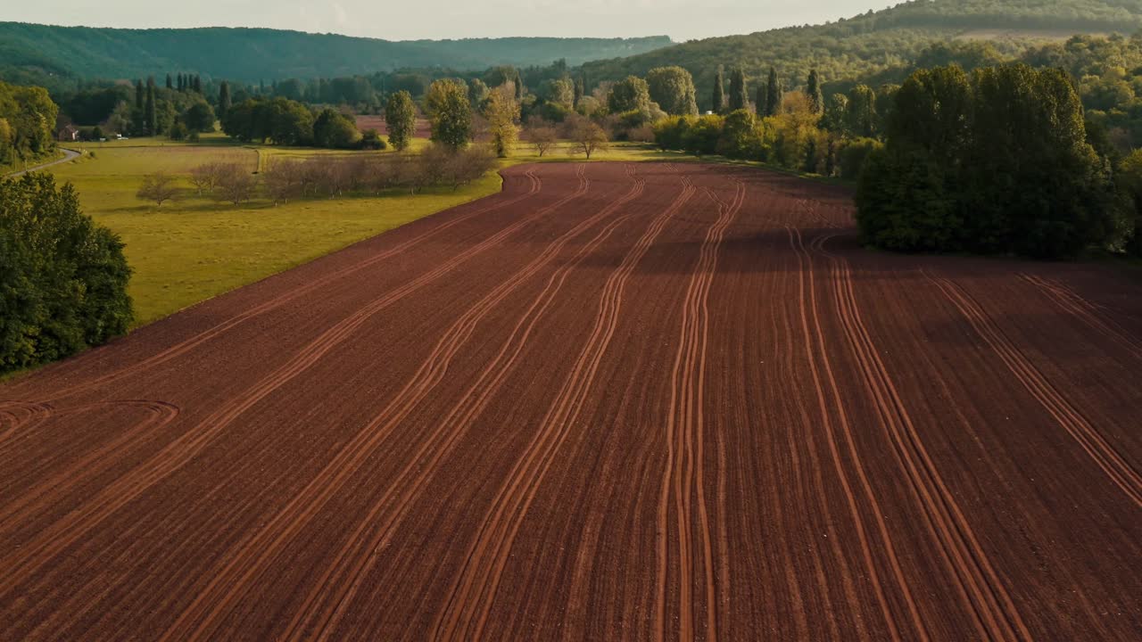 Frisch bearbeiteter Boden bildet Linien auf einem landwirtschaftlichen Feld, bereit für die Pflanzsaison, Drohnen-Dolly-Aufnahme.