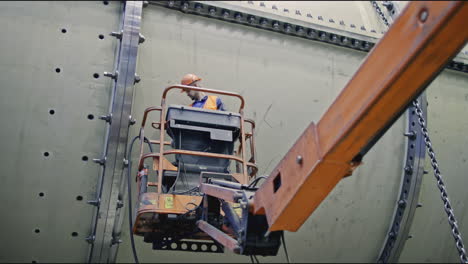 industrial worker on elevated platform repairing large vessel