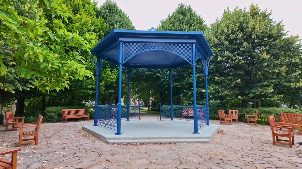 Discovering a new blue kiosk with benches in a shaded park presented for music events, Saint-Nazaire, Loire-Atlantique, France