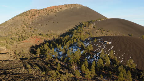 Backward-moving-aerial-showing-Cinder-cone-volcanic-mountain-at-Sunset-Crater,-Arizona