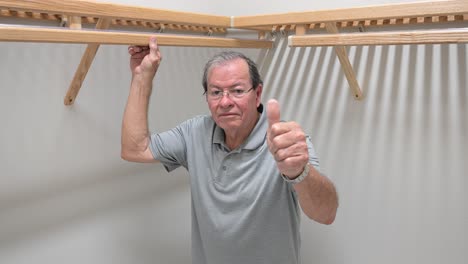 happy homeowner customer gives a thumbs-up sign to his new wooden closet shelves