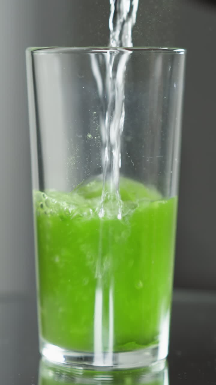 agua clara vertiendo en un vaso con una rebanada de kiwi, burbujas efervescentes en luz brillante