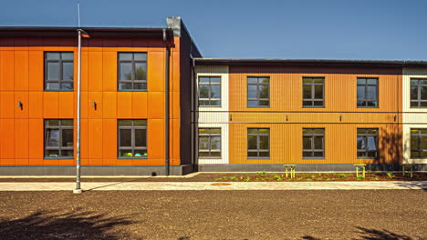 timelapse of an orange building with symmetrical windows, showcasing the shadows of vegetation in motion