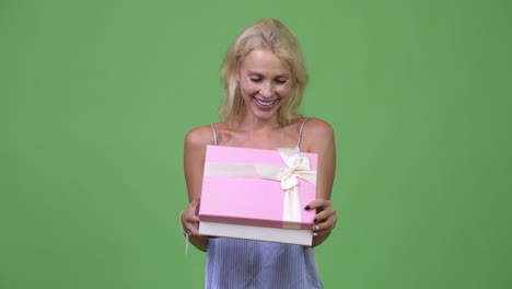 Young happy beautiful businesswoman opening gift box