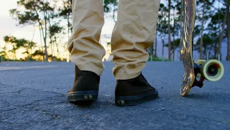 low section of young male skateboarder standing with skateboard on country road 4k