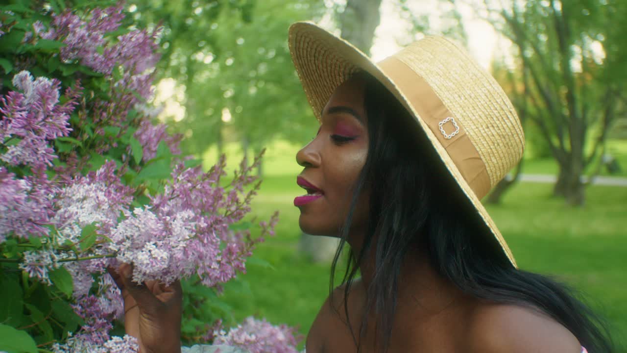 mujer negra oliendo flores lilas cerrar