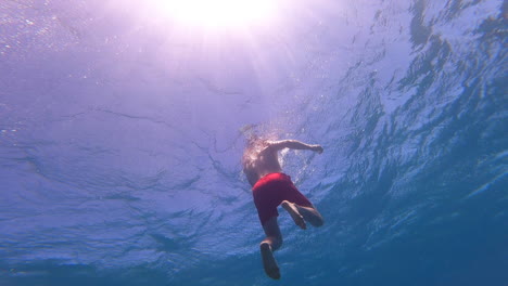 a young swimmer rises to the surface of