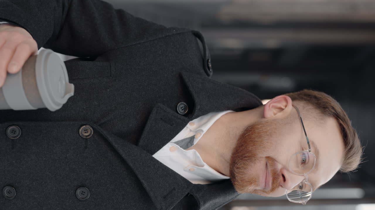 Man drinking coffee wearing a coat and eyeglasses