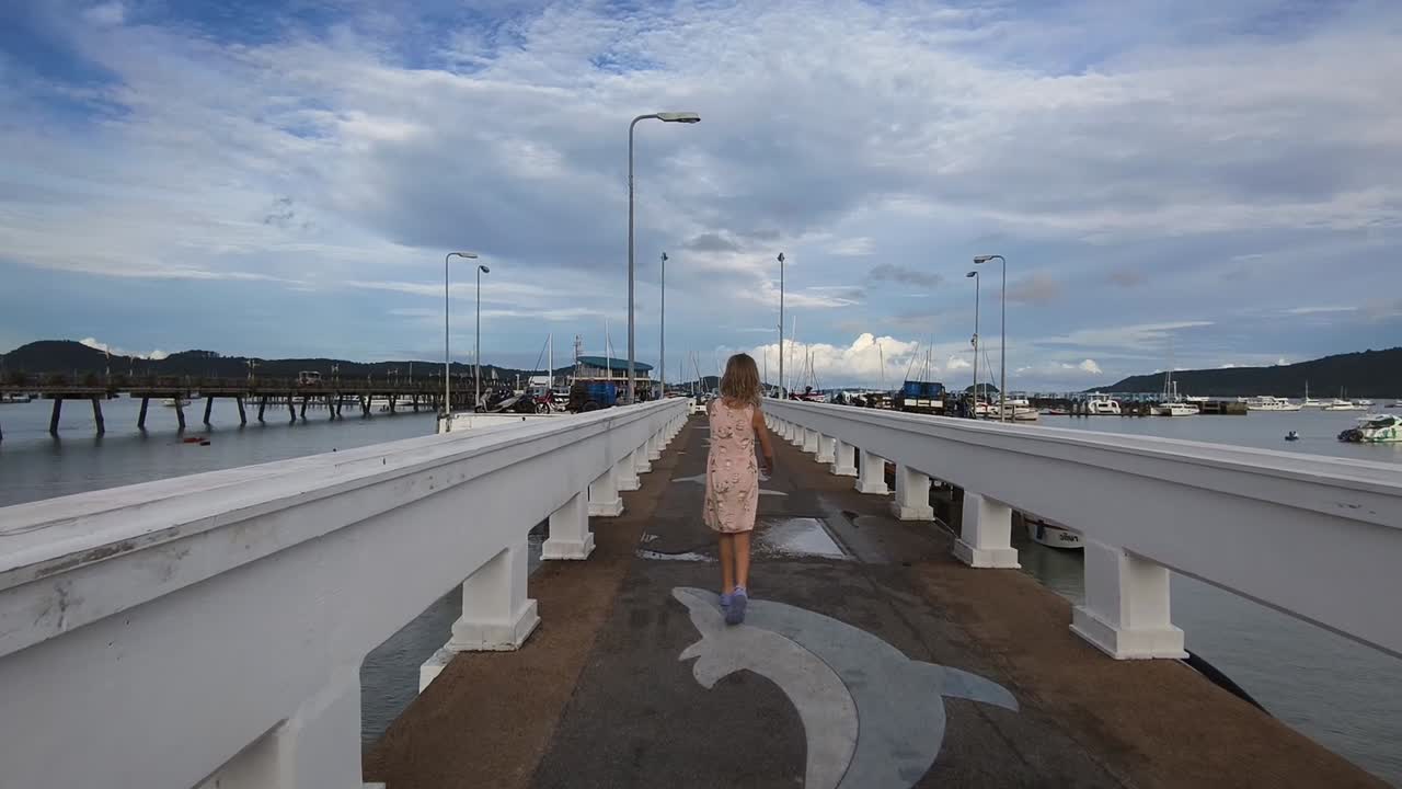 niño caminando por un muelle en un puerto deportivo