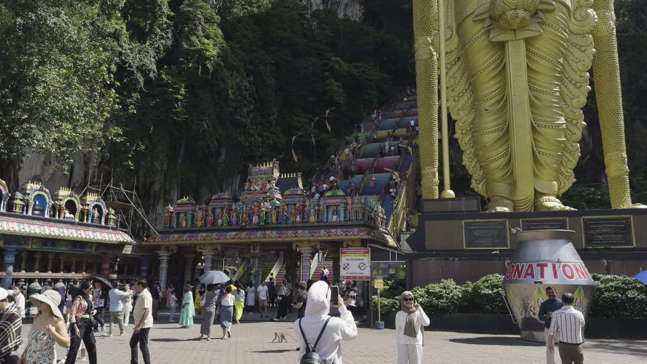 Tourists at the base of Batu Caves with a view of the giant golden Lord Murugan statue