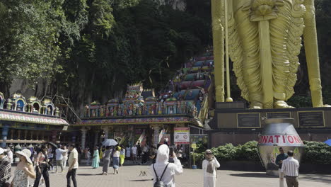 tourists at the base of batu caves with a view of the giant golden lord murugan statue