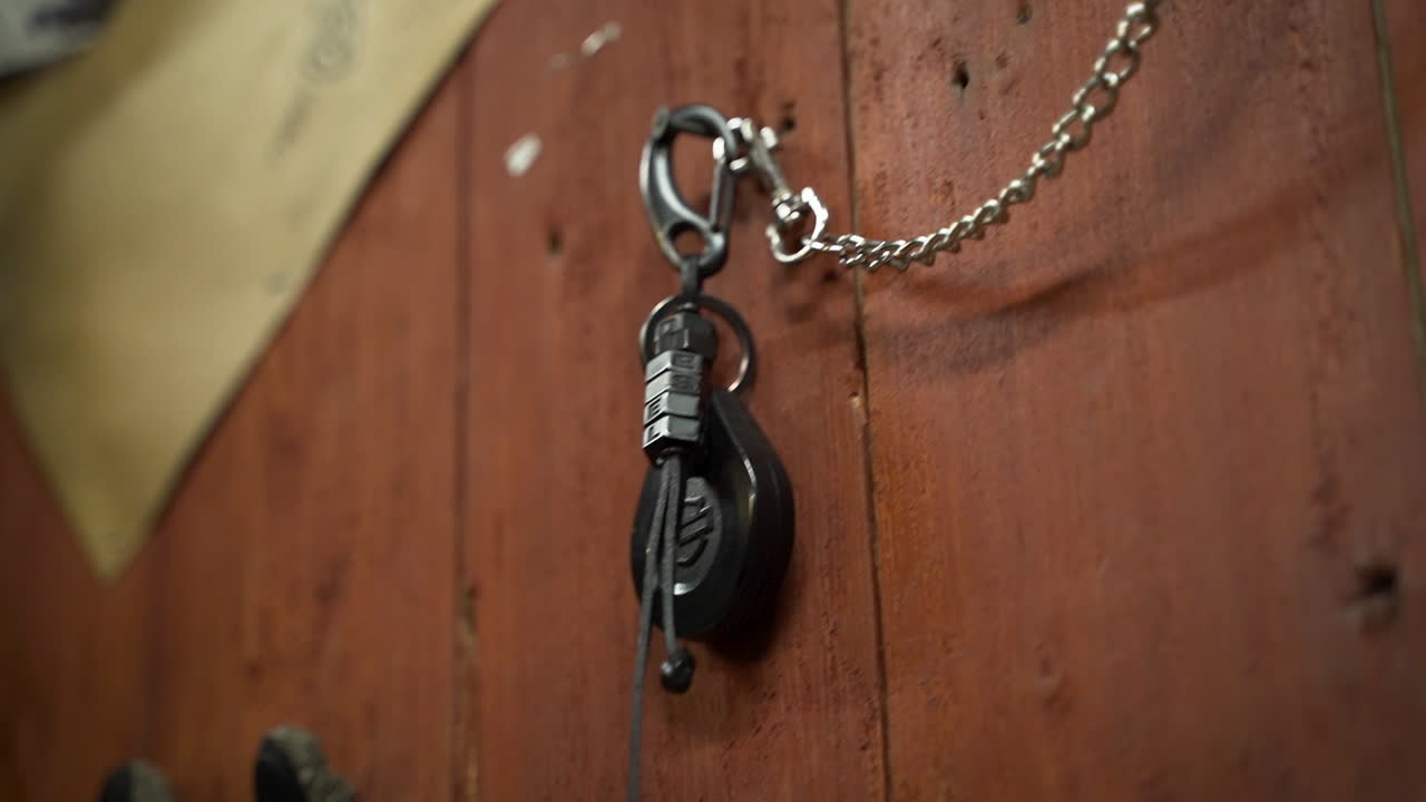 Hand attaching chain to wooden wall