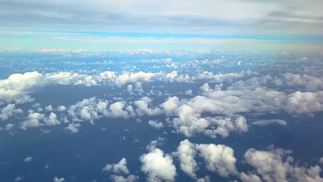 Flying-Through-Cumulus-Clouds-Seen-Through-Airplane-Window-Above-Blue-Ocean-Underneath