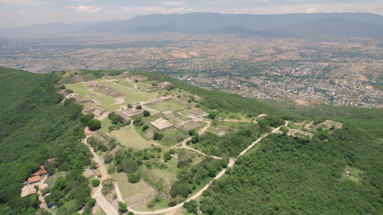 Aerial: Monte Alb&aacute;n ruins in Oaxaca, overlooking a vibrant Mexican city landscape