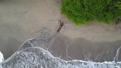 Top-down-aerial-view-of-person-sitting-on-deserted-beach-in-national-park-of-Marino-Bellena,-Costa-Rica