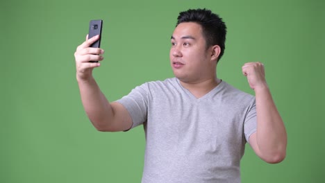 초록색 배경에 젊은 잘생긴 과체중 아시아인