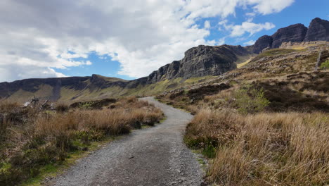 sendero de senderismo en la isla de skye con impresionantes acantilados rocosos y exuberante vegetación bajo un cielo azul