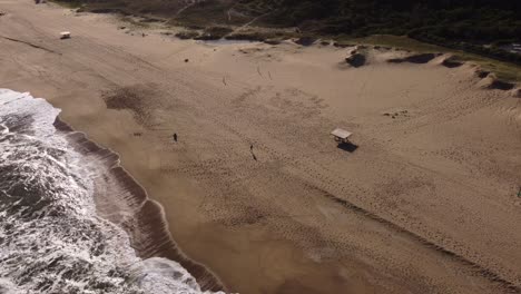 toma aérea de un hombre corriendo en una playa de arena durante un día soleado en uruguay - lección de fitness y deporte al aire libre en la costa