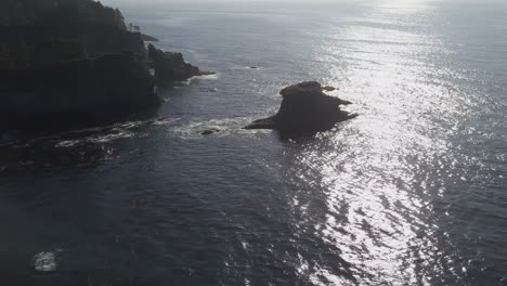 aerial to sea stack islands in calm pacific northwest ocean sun beam