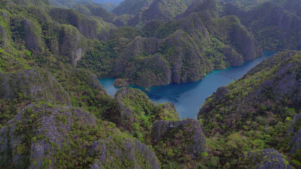 Água turquesa do Lago Kayangan de uma lagoa escondida cercada por imponentes carstes de calcário cobertos por vegetação verde exuberante. Panorama perfeito de drone com vista aérea em voo reverso
