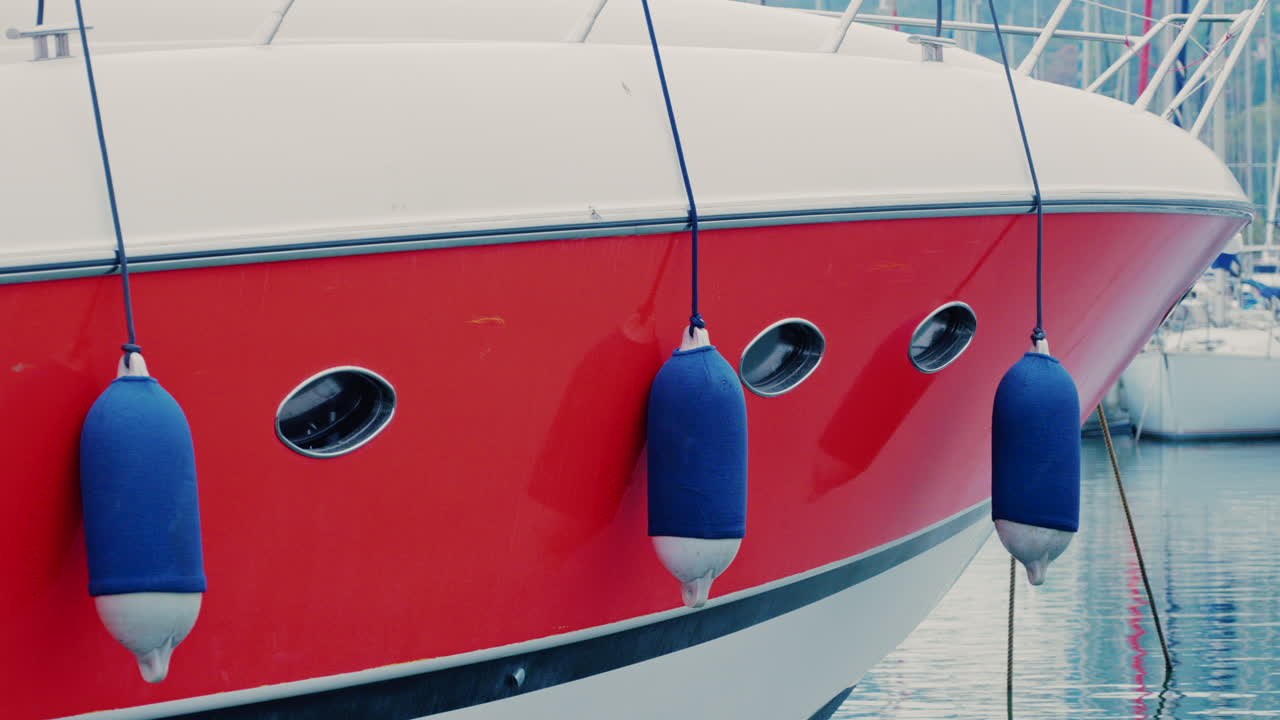 Modern red and white yacht docked in calm marina waters with clear reflections