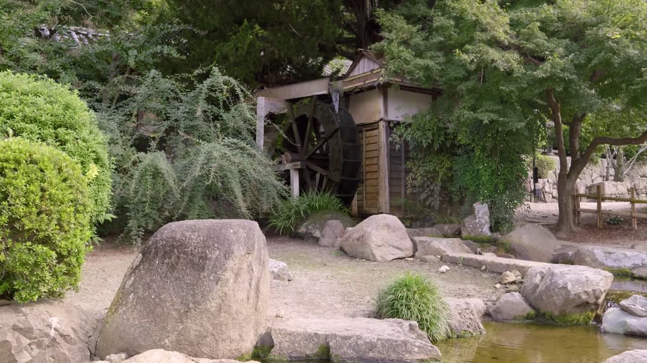 Japanese water mill. Wide handheld shot