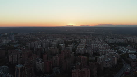 Vista-Aérea-De-Casas-De-Apartamentos-En-Una-Gran-Urbanización-En-La-Ciudad-Al-Atardecer.-Puesta-De-Sol-Detrás-De-La-Cresta-De-La-Montaña-En-La-Distancia.