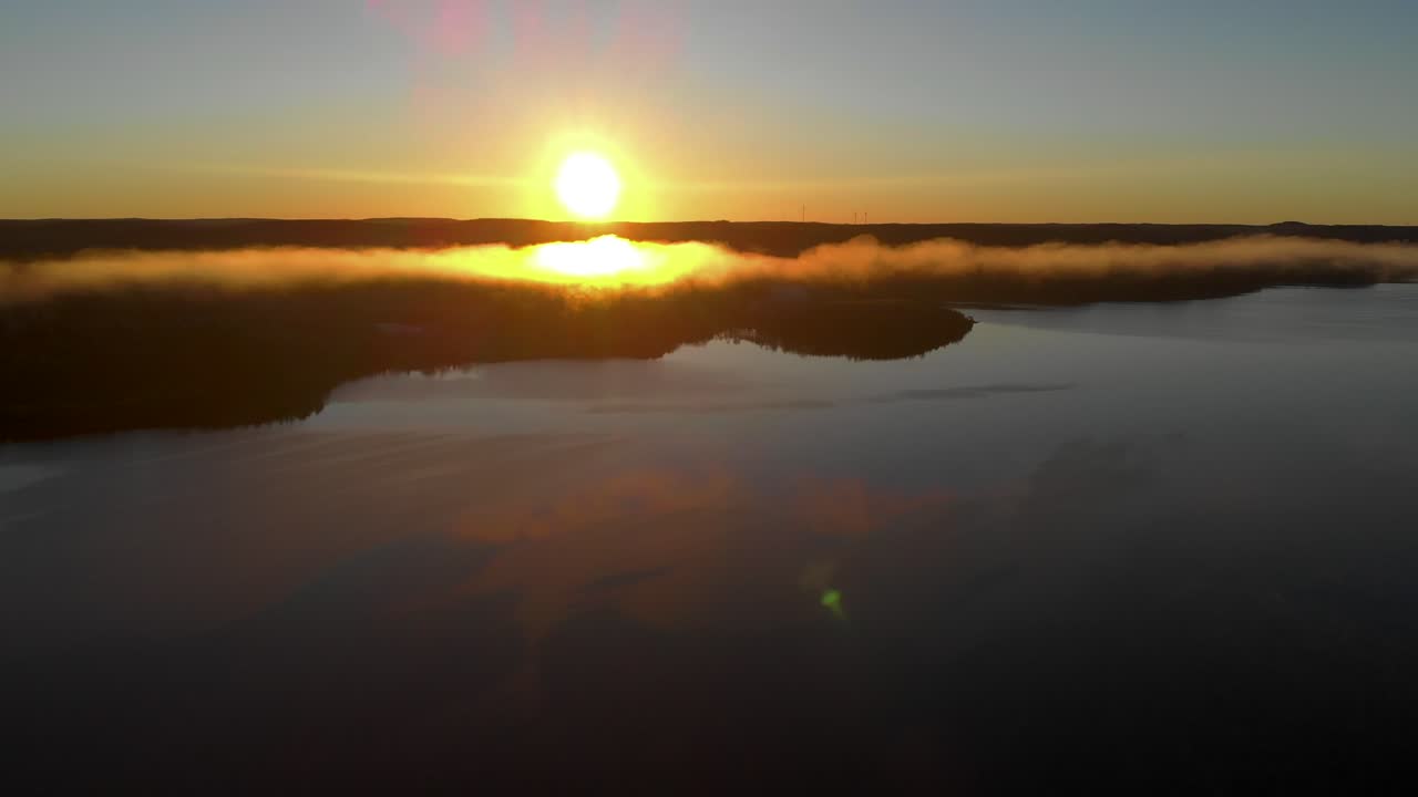 drone volando hacia adelante sobre el pacífico paisaje del río fiordo con el sol saliendo sobre el horizonte