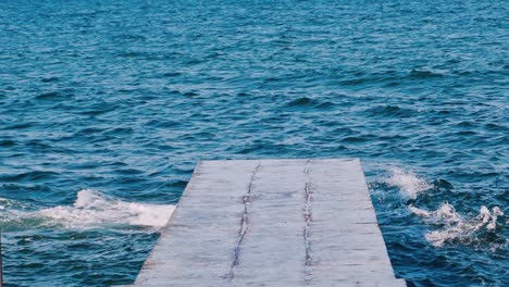 amazing view from the pier on the sea water. blue water surface. waves breaking on the dock in the sea. slow motion.