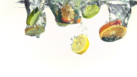 slices of oranges, limes and lemons falling into water in super slow motion