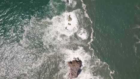 Vista-Aérea-De-Arriba-Hacia-Abajo-La-Superficie-Del-Mar-Revela-El-Faro-De-Nazaré-Mirador-En-El-Acantilado-Premonitorio