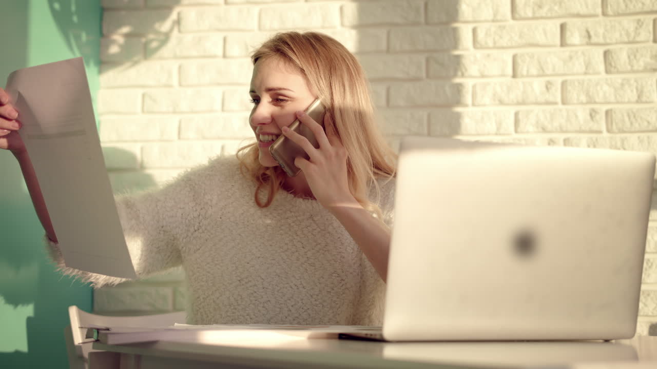 mujer trabajadora disfruta de la conversación móvil. chica alegre trabajando con documentos