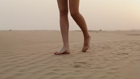 woman walking barefoot in the desert at sunset