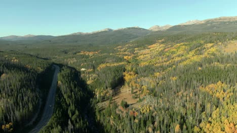 aerial pan across road with car and mountain forest