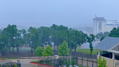 Heavy-rain-on-a-cloudy-day-with-trees-gate-entrance-and-2-buildings