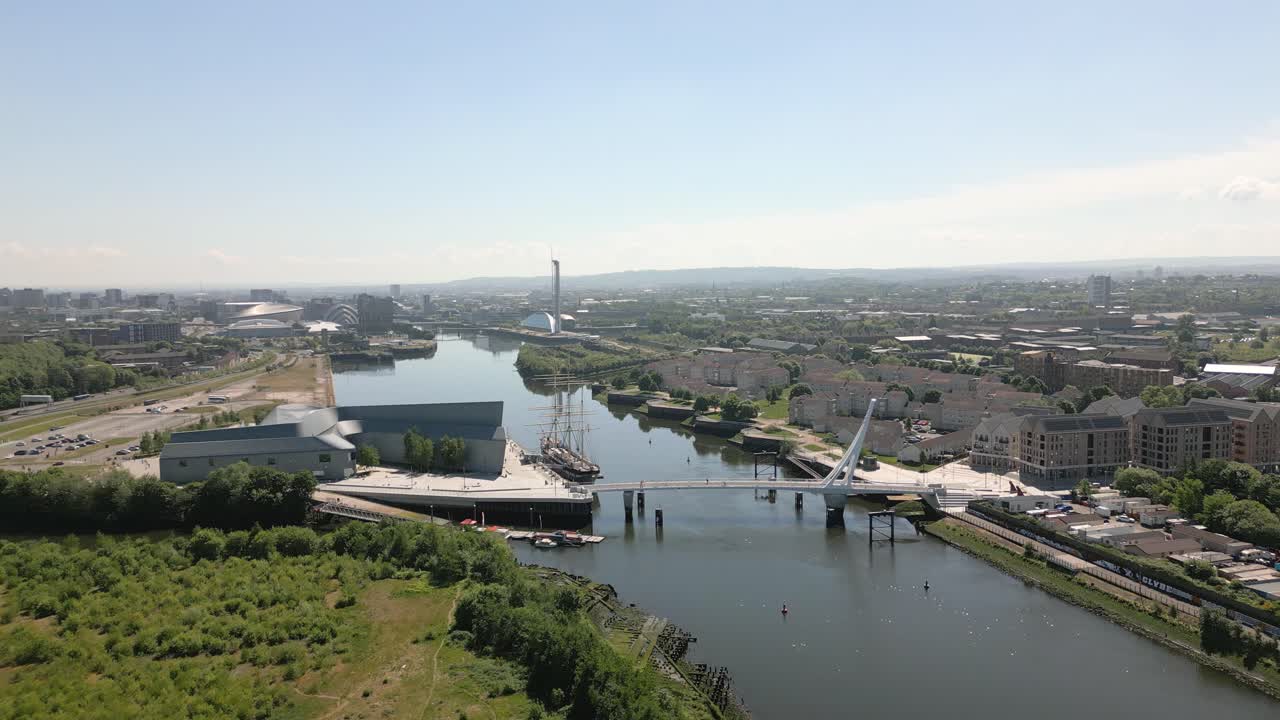 Aerial push in along the River Clyde with the Riverside Museum architecture, Govan-Partick footbridge and the Glasgow skyline in the background, Scotland, UK