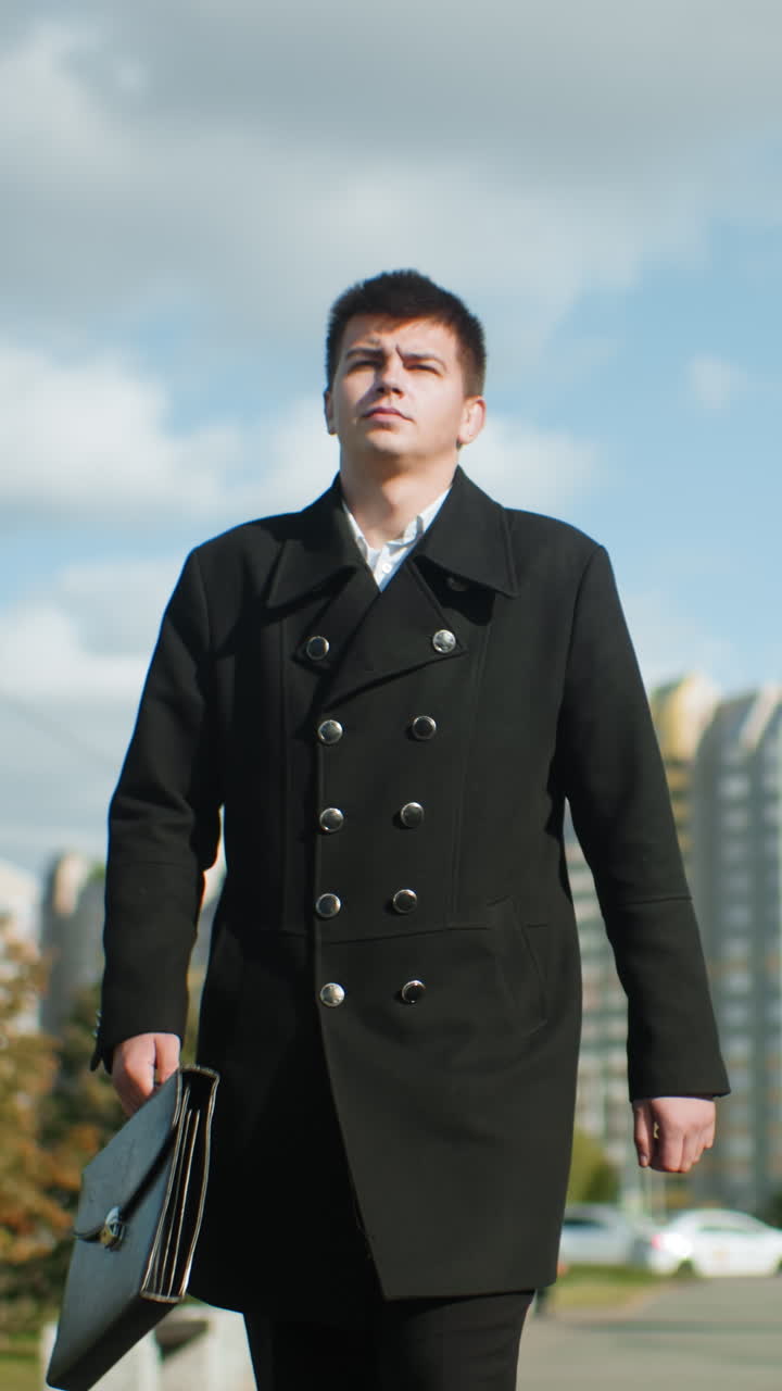 야외에서 자신감 있게 걸어가는 정치인, 브리프케이스를 들고, 잎이 바람에 날아다니며, 현대적인 유리 건물, 도시 나무, 그리고 은 파란 하늘 아래의 활기찬 환경으로 둘러싸여