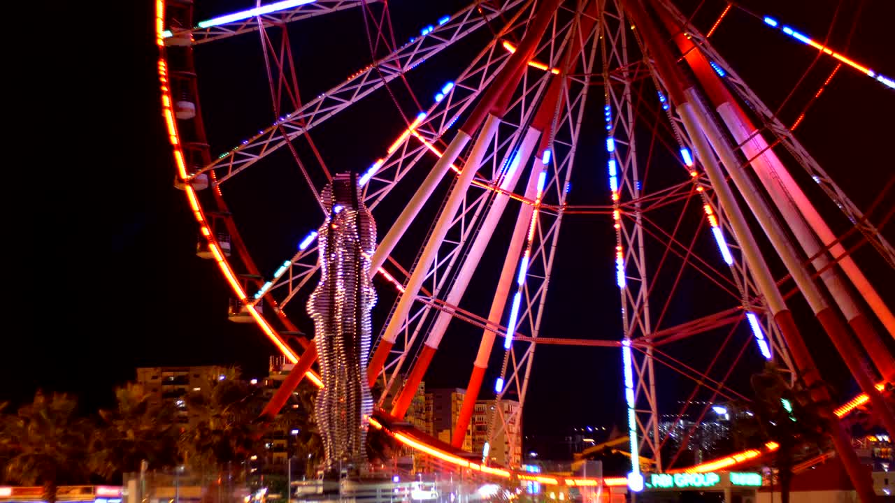 Statue of Ali and Nino on a background Ferris wheel at night on the embankment of Batumi, Georgia